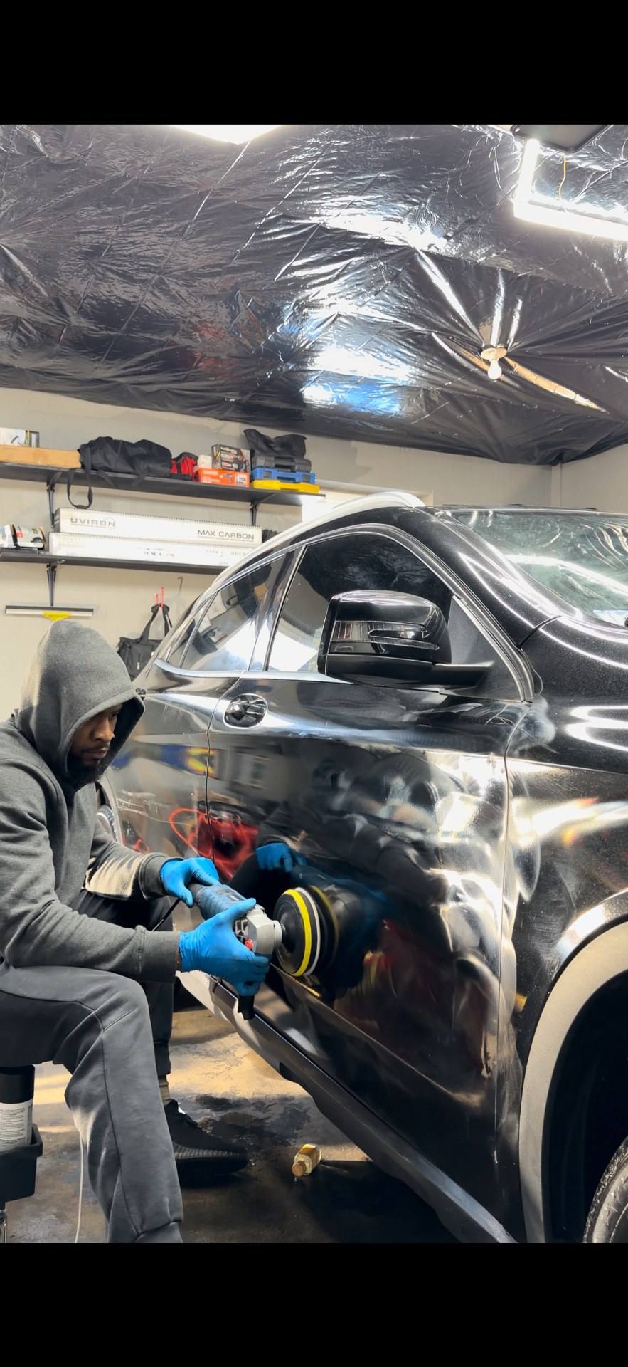 Paint correction with a dual action polisher on a black SUV at Eclipse Tint & Auto Spa
